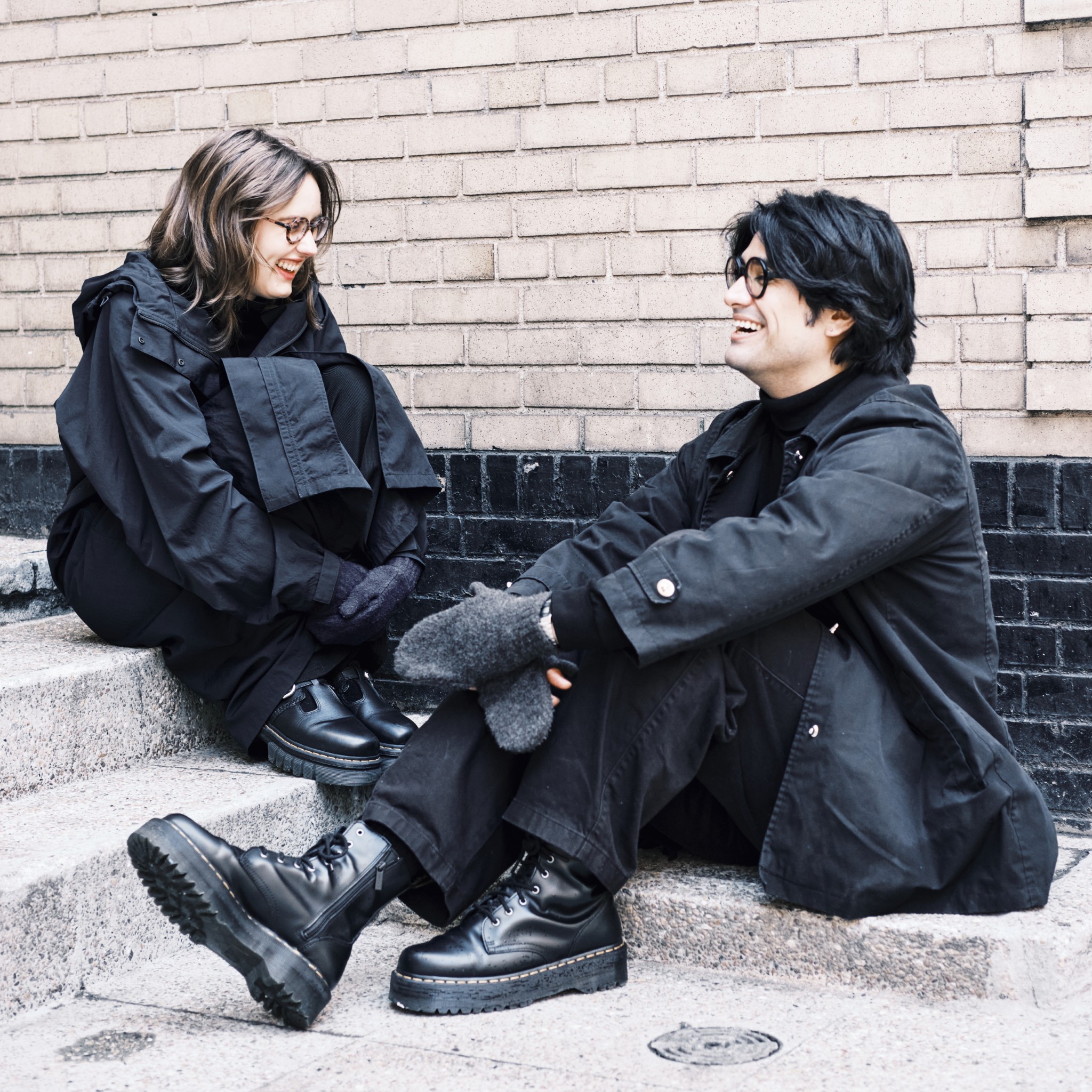 Two people laughing together on outdoor steps.