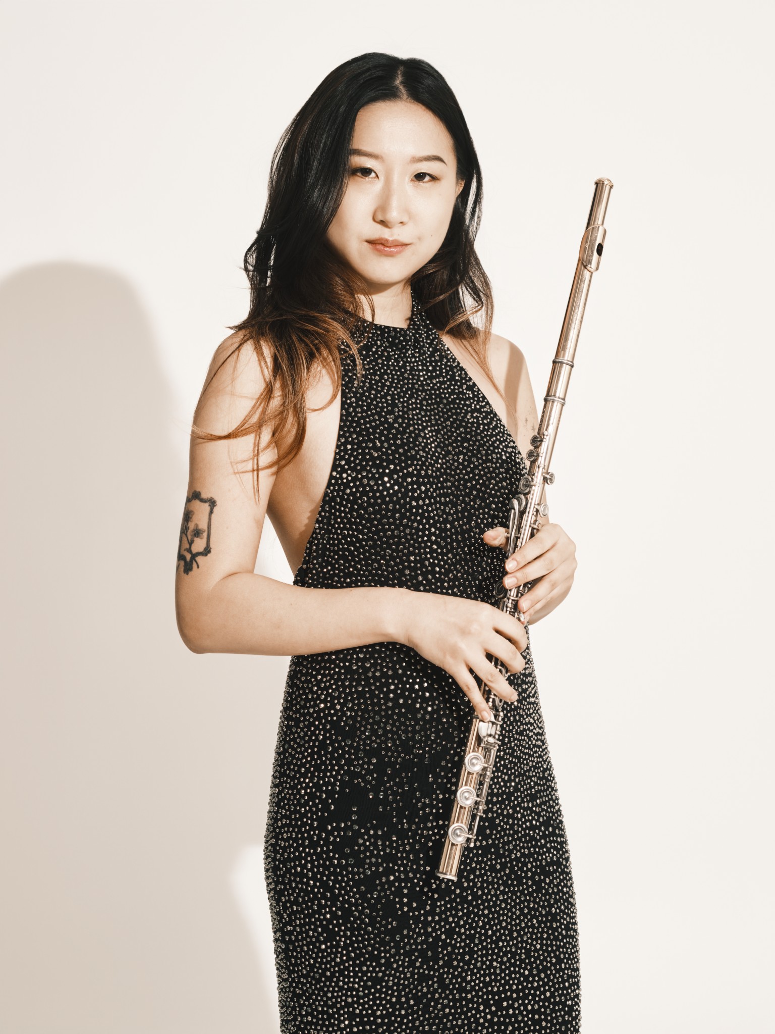 Musician in a formal black dress holding a silver flute.